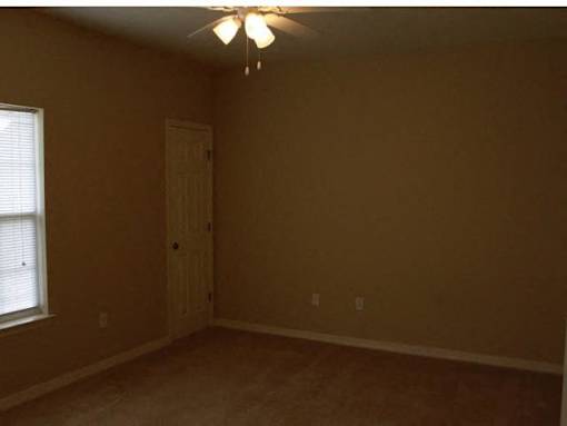 A room with a ceiling fan and a door at Arbours at Ensley Apartments, Pensacola, FL 32514