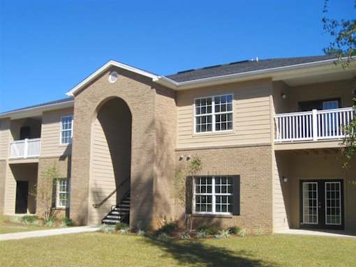 A beige building with a balcony and a staircase at Arbours at Ensley Apartments, Pensacola, FL
