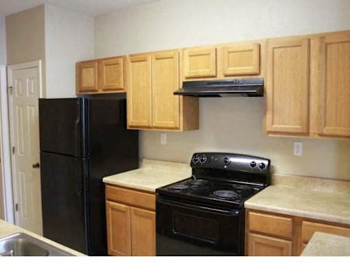 A kitchen with wooden cabinets and black appliances at Arbours at Ensley Apartments, Pensacola, Florida