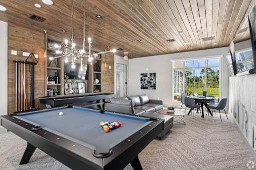 A pool table is in the middle of a room with a wooden ceiling.