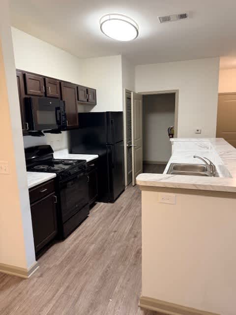 A kitchen with black appliances and a white counter.