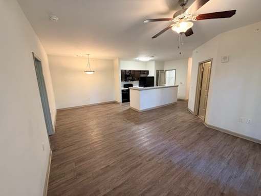 A room with a ceiling fan and wooden flooring.