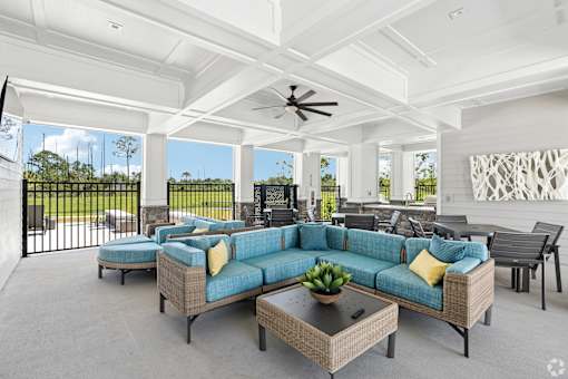 A spacious outdoor living room with a sofa set and a ceiling fan.