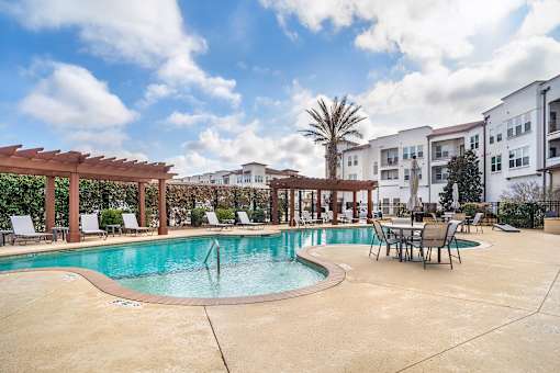 A pool surrounded by chairs and a wooden pergola at The Addison, Baton Rouge, LA 70836