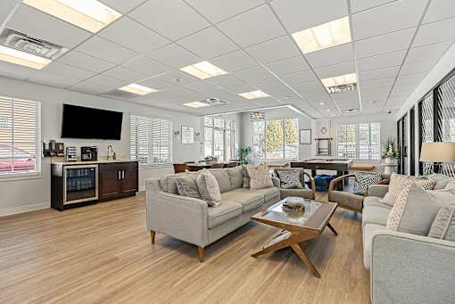 A modern living room with a grey sofa, a wooden coffee table, and a kitchen area in the background. at Chatham Hill, New Jersey, 07928