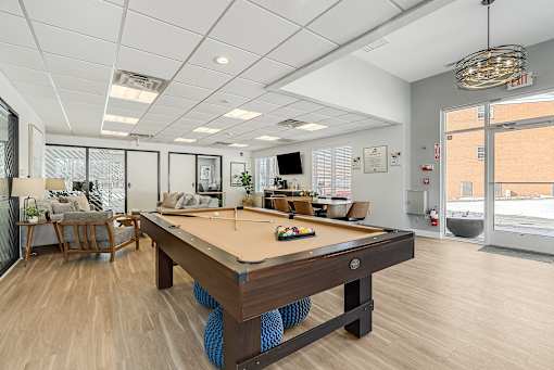 A pool table is in the middle of a room with a white ceiling and a door to the right. at Chatham Hill, New Jersey, 07928