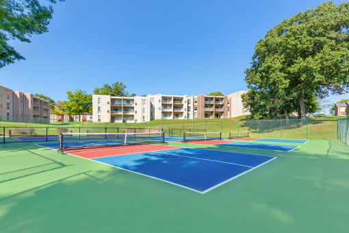 two tennis courts with apartments in the background at Copper and Quarry Village, Pikesville
