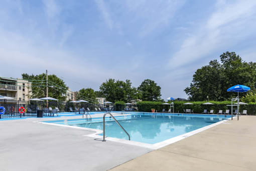 a swimming pool with umbrellas and buildings in the background at Copper and Quarry Village, Pikesville, MD, 21209