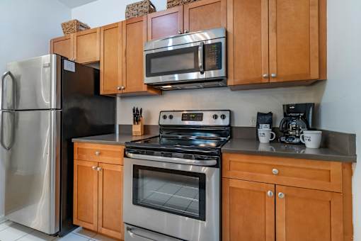 a kitchen with stainless steel appliances and wooden cabinets at Pier Village Apartments, New Jersey