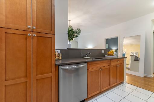 a kitchen with a stainless steel dishwasher and wooden cabinets at Pier Village Apartments, Long Branch, New Jersey