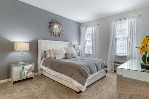 a bedroom with a bed and two windows at Pier Village Apartments, Long Branch, New Jersey