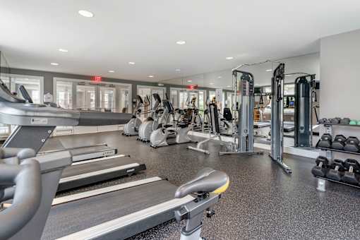 a gym with cardio equipment and weights in a building with windows at Pier Village Apartments, Long Branch, 07740