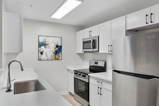 A modern kitchen with stainless steel appliances and white cabinets at Grand at Pearl Apartments, Pearl, MS