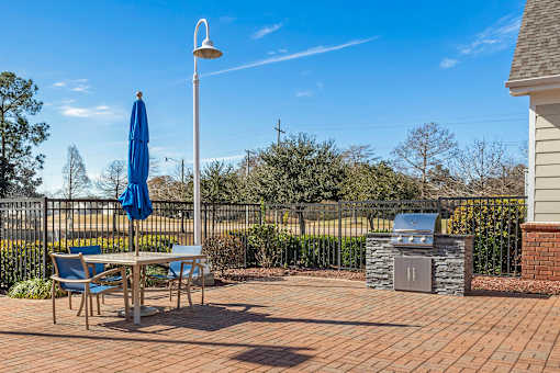 A patio with a table, chairs, and an umbrella. at Greenbrier Estates, Slidell, 70460