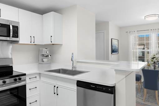 A modern kitchen with white cabinets and appliances. at Reflection Pointe, Flowood, Mississippi