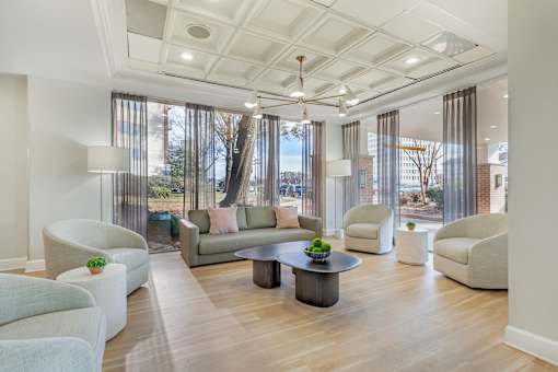 A spacious living room with a large window and a view of trees and buildings outside.