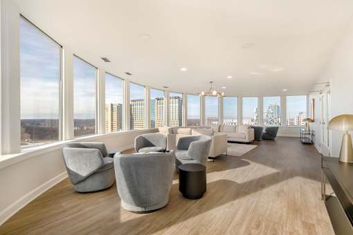 A spacious room with grey chairs and a view of the city.