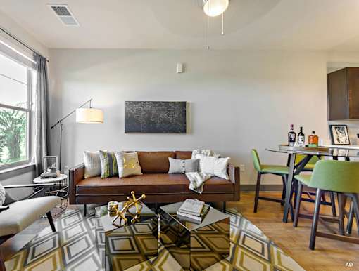 a living room and dining room with a couch and chairs and a table with a chair  at The Addison, Baton Rouge, LA