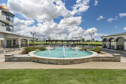 a fountain in the middle of a pool in front of a building