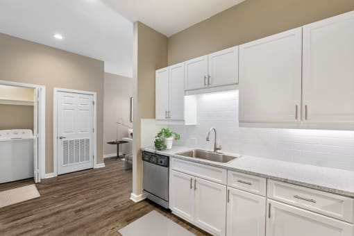 a white kitchen with white cabinets and a stainless steel sink