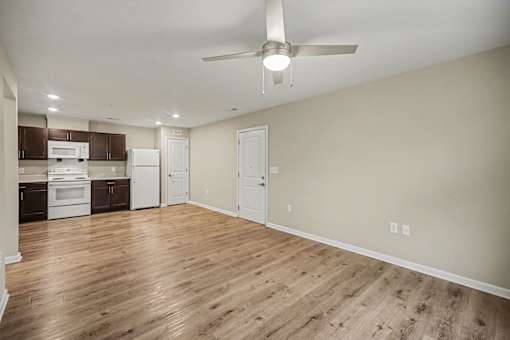 A kitchen with white appliances and wooden floors.