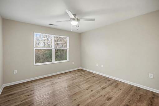 A room with a ceiling fan and a window with blinds.