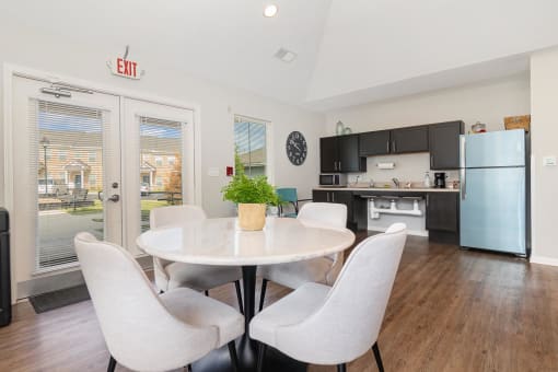 a dining area with a table and chairs and a kitchen in the background