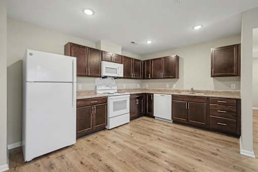 A kitchen with white appliances and wooden cabinets.