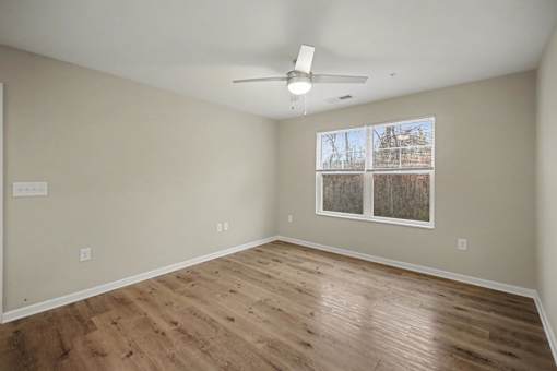 Empty room with wood flooring and a ceiling fan.