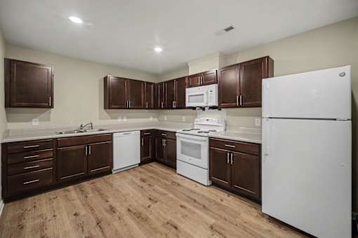 A kitchen with white appliances and brown cabinets.