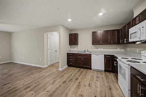 A kitchen with white appliances and brown cabinets.