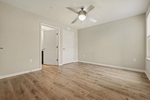 A room with a ceiling fan and wooden flooring.