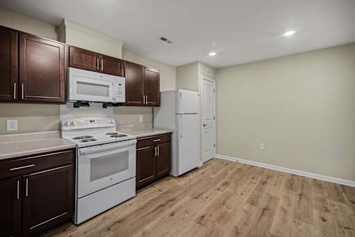 A kitchen with brown cabinets and white appliances.