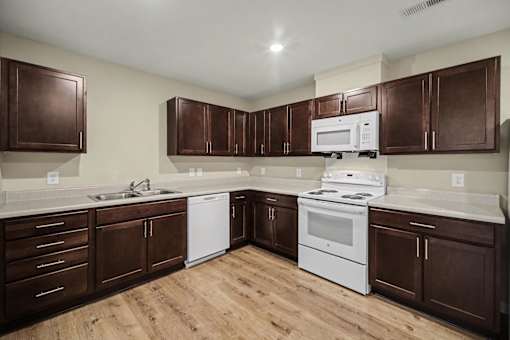A kitchen with brown cabinets and white appliances.