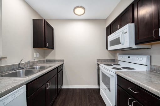 a kitchen with white appliances and dark cabinets