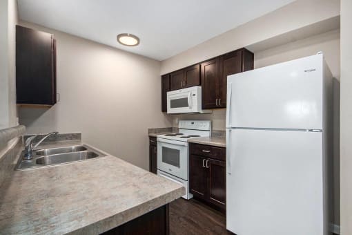 a kitchen with white appliances and dark wood cabinets
