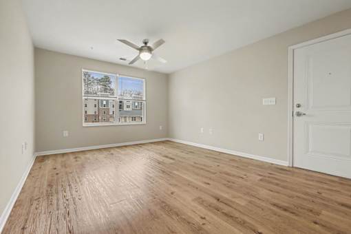 A room with a ceiling fan and a picture of a house on the wall.