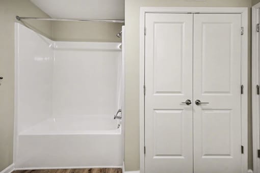 A white bathroom with a walk-in shower and a white door.
