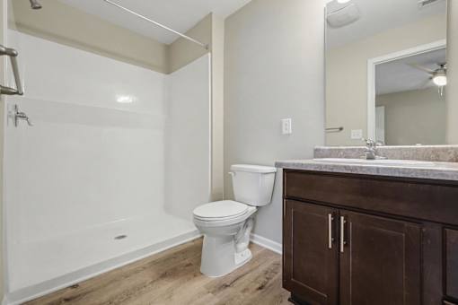 A white toilet sits in a bathroom next to a walk-in shower.
