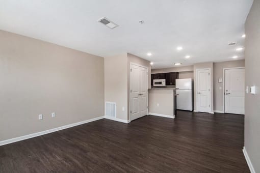 the living room and kitchen of an apartment with a hard wood floor