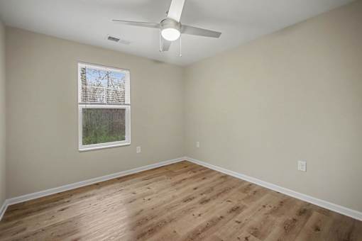 A room with a ceiling fan and a window with blinds.