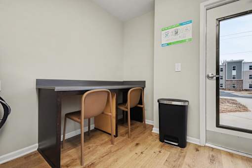 A room with a desk and chairs and a trash can.