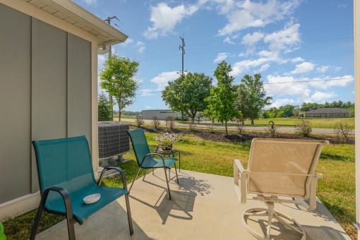 a patio with two chairs and a table with flowers on it
