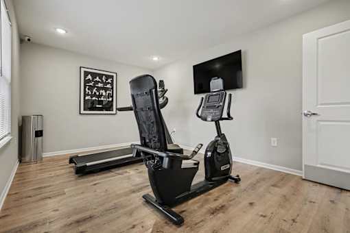A home gym with a treadmill, a stationary bike, and a weight machine.