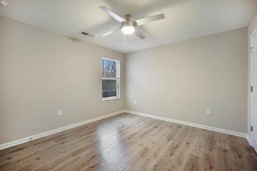 A room with a ceiling fan and wooden flooring.