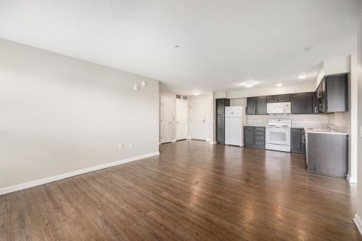 an empty living room and kitchen with wood floors