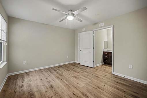 A room with a ceiling fan and wooden flooring.