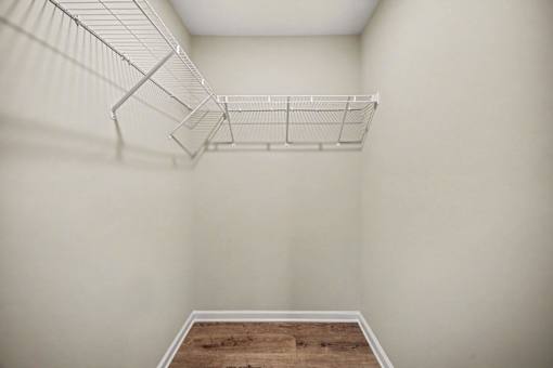 A white wire shelf is mounted on a white wall above a wooden floor.