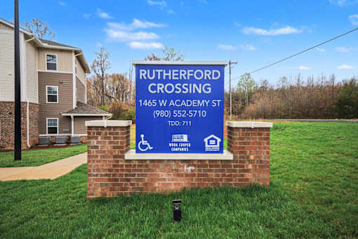 A sign for Rutherford Crossing is displayed in front of a grassy area.