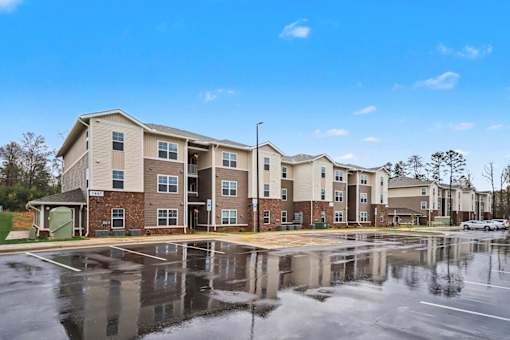 A large apartment complex with a parking lot in front.